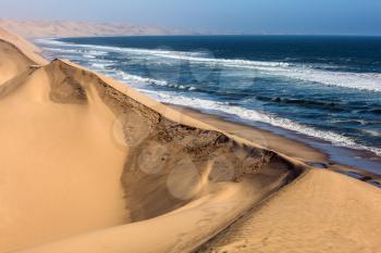 Atlantic coast of Walvis Bay, Namibia, south of Africa. Ocean surf with foamy waves. Jeep - safari through the huge sand dunes. The concept of extreme and exotic tourism