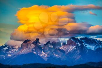  Magnificent orange clouds in the rays of the sunset.  The black cliffs of Los Cuernos. The concept of extreme and active tourism. Torres del Paine National Park