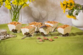  Sweet portioned dessert from mousse halva, sprinkled with grated caramel. Background light green, flowers in vases and a silver spoon. Professional bakery