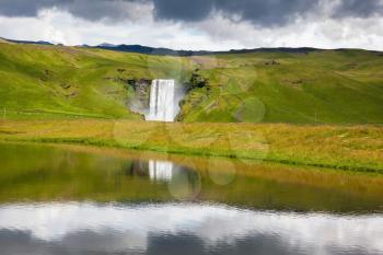 An incredible reflection. Abounding waterfall Skogafoss reflected in a small pond near the road