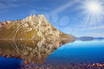 Picturesque mountain and lake in Bariloche, Argentina. The concept of exotic and extreme tourism. The summer sun illuminates the picturesque landscape