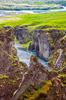The striking canyon in Iceland. The concept of active northern tourism. Bizarre shape of cliffs surround the stream with glacial water