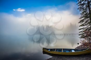 Fishing boats moored on the shore. Emerald Lake in Yoho National Park. Foggy morning