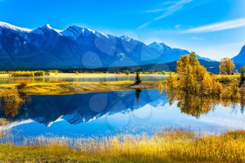 The water of fantastic Abraham lake reflects mountains and trees. Sunny autumn day in the Rocky Mountains of Canada. The concept of ecological and active tourism