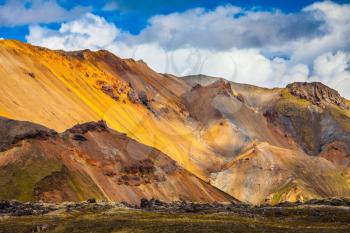 Bright, multi-colored rhyolite mountains - yellow, orange, green and blue. Summer volcanic tundra.  Travel to Iceland in July