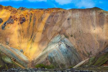Multi-colored mountains from mineral rhyolite are lit with the July sun. Travel to Iceland in the summer. National park Landmannalaugar