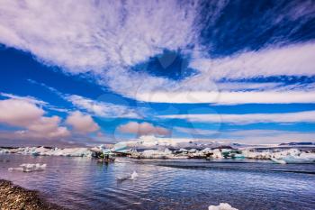 Clouds reflected in the water of lagoon. The concept of northern extreme tourism. The ice floes and cirrocumulus clouds of lagoon Jokulsarlon, Iceland