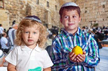 Two beautiful Jewish boys in skull-caps with etrog. Autumn Jewish holiday Sukkot.  The greatest shrine of Judaism is the Western Wall of the Temple