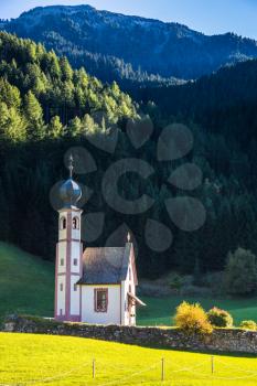  The church of Santa Maddalena. Tirol, Dolomites. Rocky peaks and forested mountains surrounded by green Alpine meadows. Sunny warm autumn day