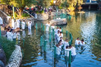 YARDENIT, ISRAEL - JANUARY 21, 2012: Christian pilgrims baptized in the Jordan River. They enter the water, dressed in special white robes