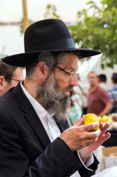 JERUSALEM, ISRAEL - OKTOBER 16, 2016: Traditional market before the holiday of Sukkot. Religious middle-aged Jew with gray beard is checking plant citrus - etrog