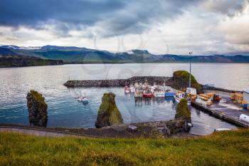 Sunset on the fjord in Iceland. White and red fishing boat in the harbor pier village Arnastapi