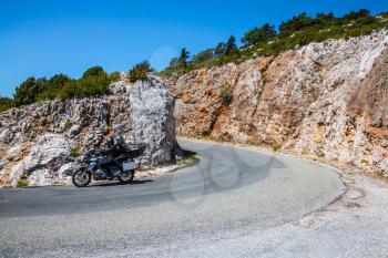 Pair of motorcyclists at high speed on a steep mountain road turn