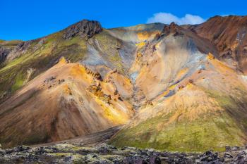  Travel to Iceland in the July. Summer volcanic tundra. Multi-colored mountains from rhyolite are lit with sun