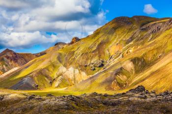  Travel to Iceland in the July. Summer volcanic tundra. Multi-colored mountains from mineral rhyolite are lit with sun
