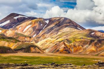  Summer volcanic tundra.  Bright, multi-colored rhyolite mountains - yellow, orange, green and blue. Travel to Iceland in July
