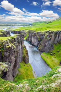  Bizarre shape of cliffs surround the stream with glacial water. The striking canyon in Iceland. The concept of active tourism