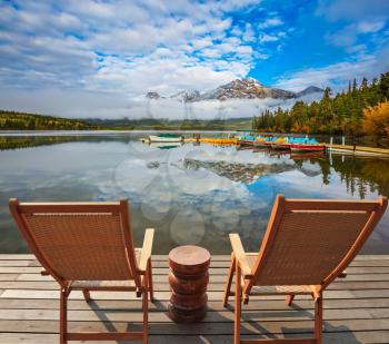  Concept of  vacation and tourism. Two deck chairs on a wooden platform. Boat station waiting for touristst. Pyramid Mountain, Jasper National Park
