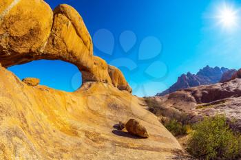 Picturesque stone arches are painted by iron oxides in red-orange color. Nature reserve Spitzkoppe in Namibia. Sunrise