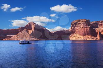 Walk on white boat on a sunny day. Scenic huge artificial water basin of the Colorado River, USA. Lake Powell is surrounded by magnificent sandstone hills