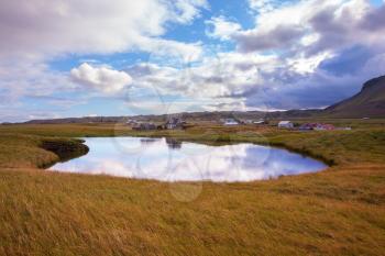 Small pond in the fishing settlement of Arnastapi. Quiet summer evening on the coast of Iceland