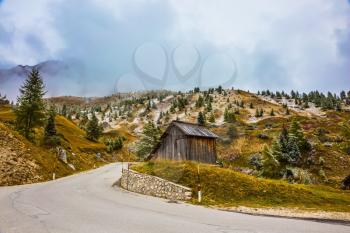 Wooden shed on the bend in the road. Dolomites in Northern Italy. First snow on the pass Giau 