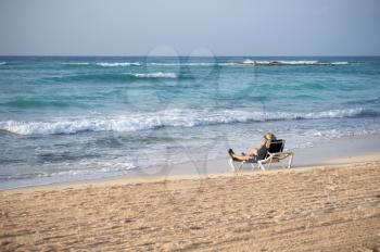 Man sitting on a beach chair by the ocean enjoying the view of the Caribbean Sea in the Mayan Riviera
