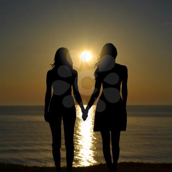 Back view of two women on holiday travel vacation beach watching sunrise