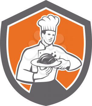 Illustration of a chef cook holding serving serve plate platter with chicken set inside shield crest on isolated background done in retro style. 