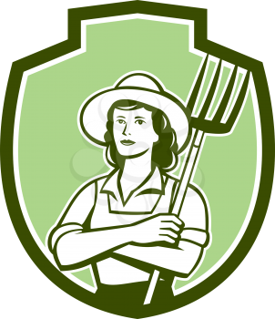 Illustration of a female organic farmer with pitchfork with hat facing front set inside shield crest on isolated bakcground done in retro style.