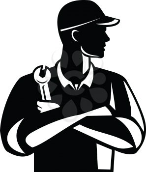 Illustration of an automotive mechanic or aircraft, electrical mechanic holding a spanner or wrench with arms crossed looking to side on isolated background done in retro black and white style.