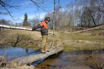 Royalty Free Photo of a Boy Standing on a Log Over Water