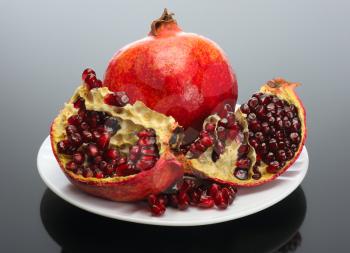 Royalty Free Photo of a Pomegranate and an Open One on a Plate