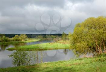 Royalty Free Photo of a River With a Grassy Island on a Cloudy Day