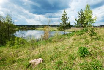 Royalty Free Photo of a Nature Scene With Water and Green Field Under a Cloudy Blue Sky