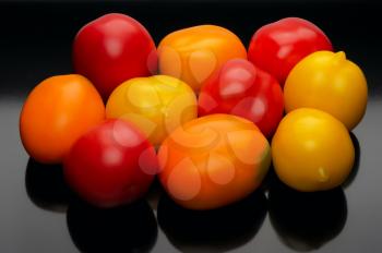 Red and yellow tomatoes on a black background