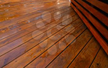 Backyard wooden deck floor boards with fresh brown stain, angled view