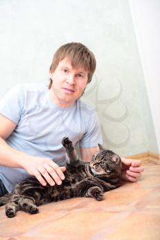 relaxed man lying on the floor with cat against wall