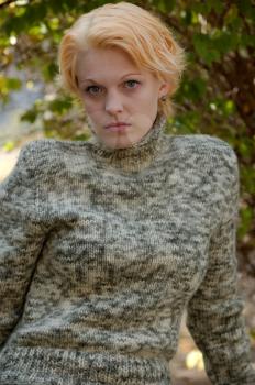 Beautiful Strawberry Blonde Woman in a Sweater at a Park Alone