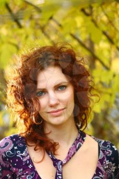 Portrait of a redheaded girl near a tree (autumn colors).