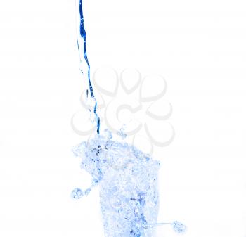 Yelllow drink being poured in a transparent glass with splashes on white