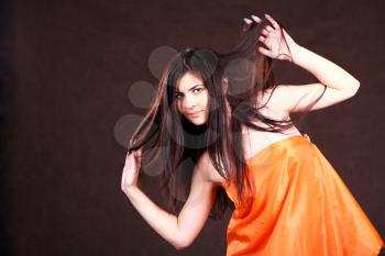 Attractive girl in orange fabric studio shot over brown background