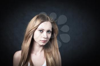 Portrait of a young blond lady on black background