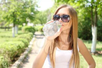 Portrait of beautiful smiling woman with bottle of water, outdoors