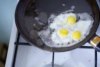 Broken egg frying in a pan