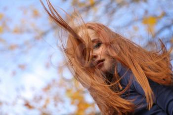 Close-up portrait of a beautiful red-headed girl posing outdoors
