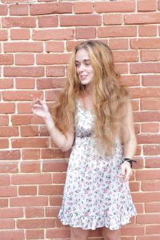 torso portrait of beautiful blonde girl in vintage dress standing near brick wall  and enjoing