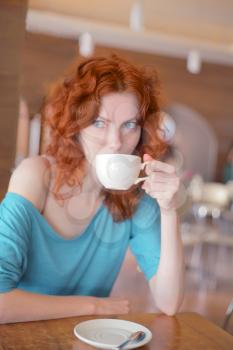 Beautiful young woman with a cup of coffee at a cafe