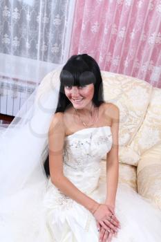Beautiful bride in elegant wedding dress with long hair sitting in chair 