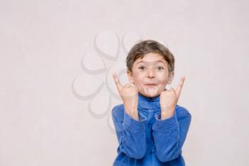 Cute little boy making funny faces on beige background